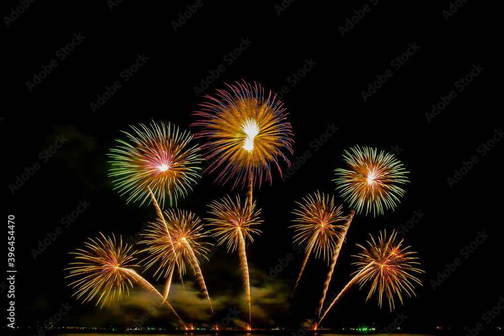 colorful fireworks,Beautiful multi color fireworks explosions lighting sky over trees silhouette and over an illuminated,celebration concept