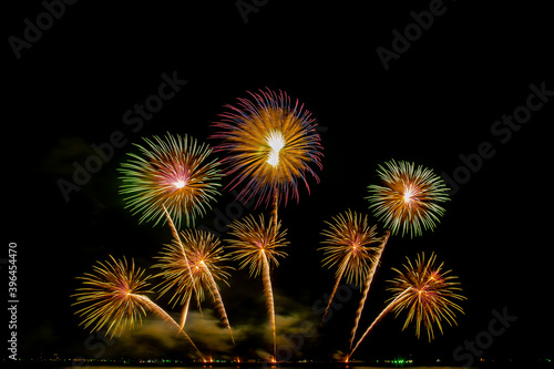 colorful fireworks Beautiful multi color fireworks explosions lighting sky over trees silhouette and over an illuminated celebration concept