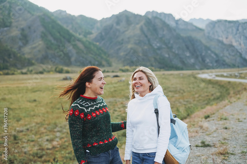 Happy young women travellers on road against the beautiful mountain landscape