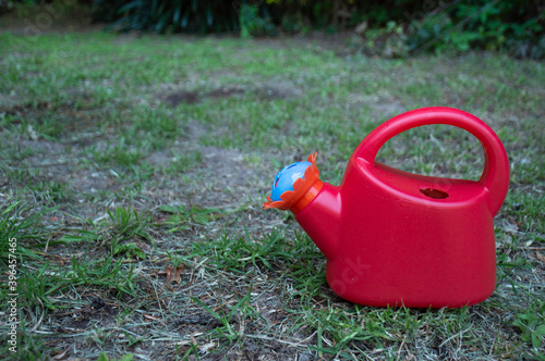 Obraz na płótnie Red toy watering can in a garden w salonie