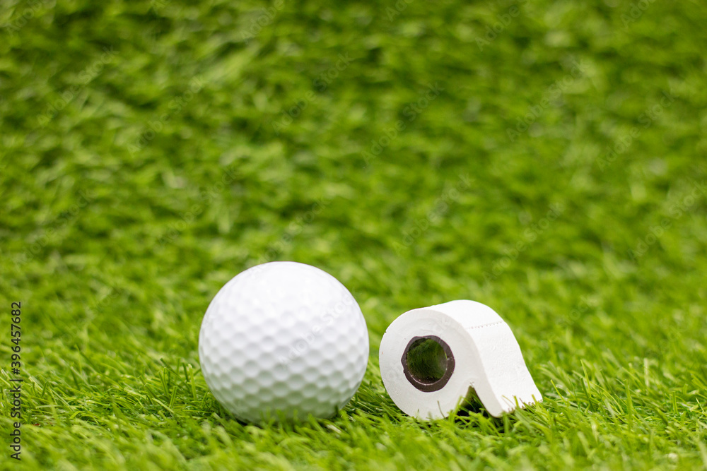 Naklejka premium Golf ball with toilet roll on green grass