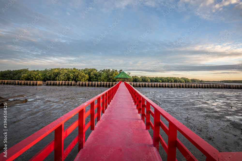 Obraz premium Golden natural sea sunrise view of Mangrove forest and wooden bridge with orange sky landscape at Bangkhuntien, Bangkok, Thailand.