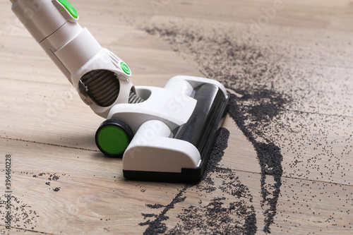 Billede på lærred A man uses a bagless vertical cordless vacuum cleaner to clean the floor