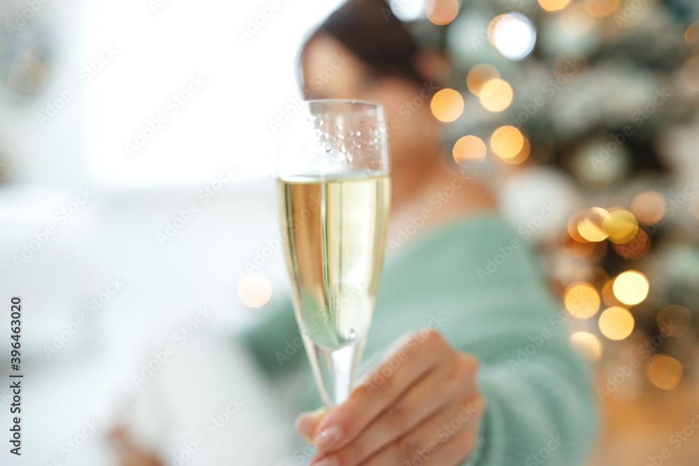 Smiling woman with glass of sparkling wine under Christmas tree lights background. High quality photo Smiling woman with glass of sparkling wine under Christmas tree lights background. High quality photo
