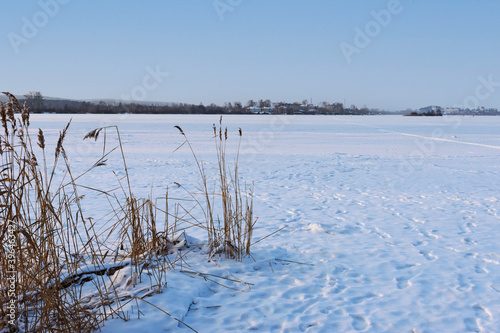 Winter view of the frozen river with the settlement on the opposite Bank