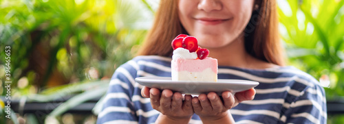 Closeup image of a beautiful young asian woman holding a piece of strawberry cheese cake in a plateCloseup image of a beautiful young asian woman holding a piece of strawberry cheese cake in a plate photo