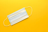 .One medical mask on a yellow background. Concept of protection against coronavirus infection