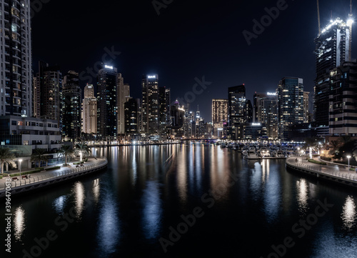 Dubai Marina Yacht Club long exposure vintage look at night with lights of skyline and creek for luxury vacation and travel