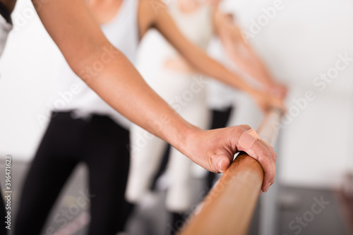 Dancers putting hand on barre . Close up