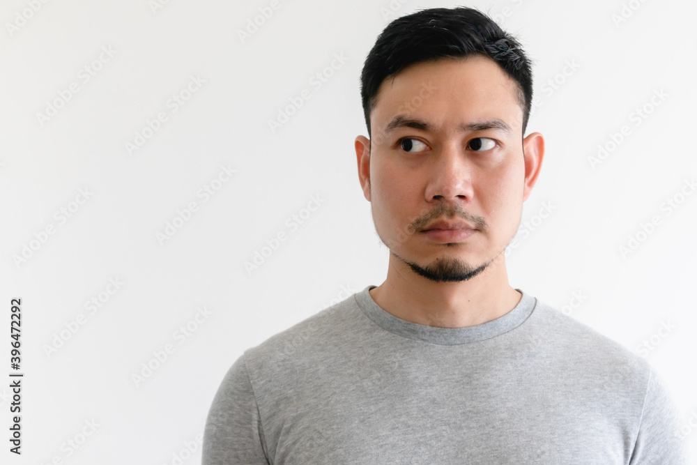 Asian man in a grey t-shirt is looking at the empty space on isolated white background. Asian man in a grey t-shirt is looking at the empty space on isolated white background.
