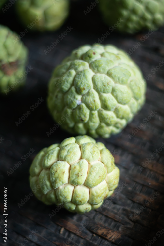 Selective focus of custard apple on old bamboo basket. Organic fruits from kitchen garden in Thailand. Selective focus of custard apple on old bamboo basket. Organic fruits from kitchen garden in Thailand.