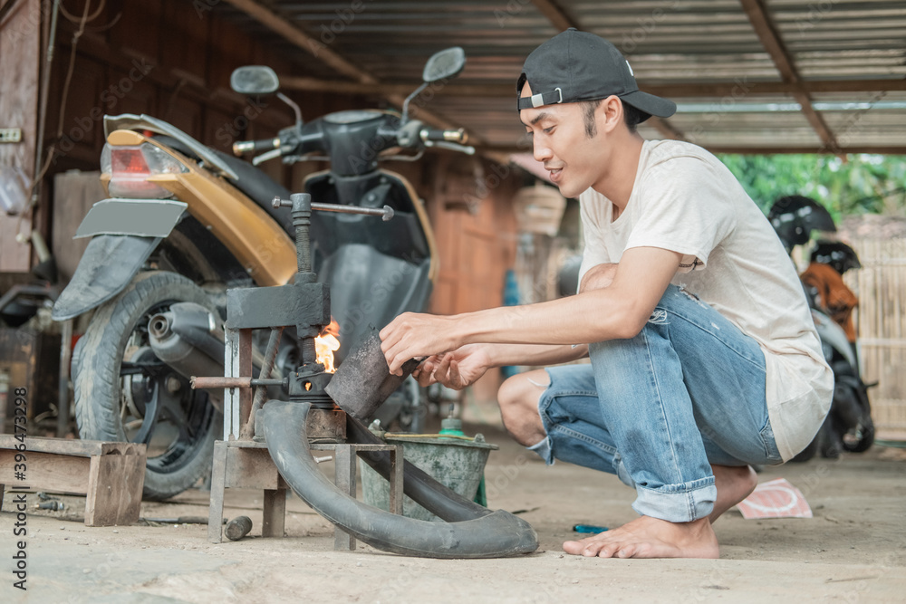 Tire repairman lights a fire with a lighter on a traditional press while patching a motorcycle tire in a tire repair shop