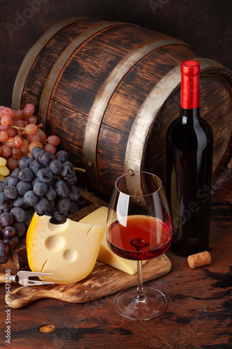 Wine bottle, grapes, cheese and glass of red wine