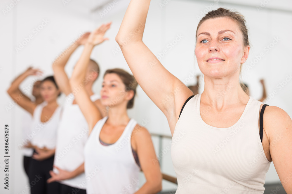 Closeup of group of women and men with their hands up during a ballet class at school