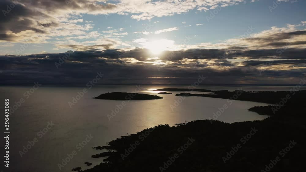 Beautiful panning up sunrise aerial above Sugarloaf Mountain looking towards Presque Isle peninsula and islands in Lake Superior with the sun shining between clouds and reflecting off of the water. Beautiful panning up sunrise aerial above Sugarloaf Mountain looking towards Presque Isle peninsula and islands in Lake Superior with the sun shining between clouds and reflecting off of the water.