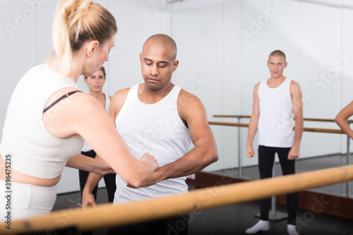 Ballet teacher adjusting foot positions in dance class