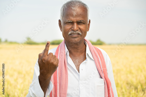 Indian farmer showing ink marked finger after voting during Indian election in hot sunny day new agriculture farmaland.