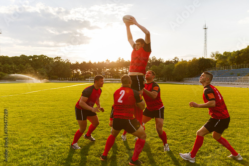 фотографія Full length image of a group of men in sports equipment play rugby on a sports field outside