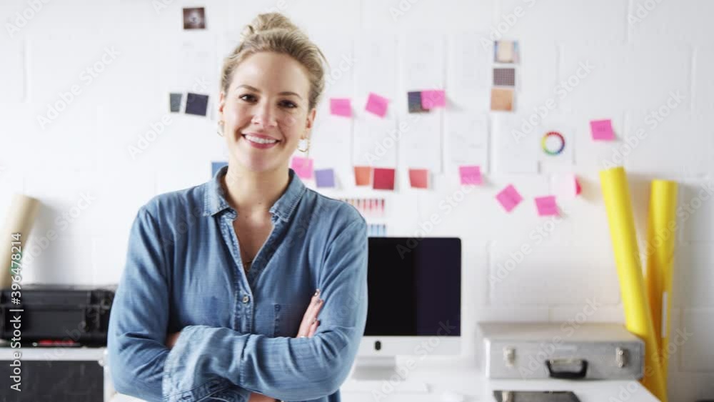 Portrait of mature businesswoman walking into focus and standing in front of desk in studio of start up fashion business - shot in slow motion Portrait of mature businesswoman walking into focus and standing in front of desk in studio of start up fashion business - shot in slow motion