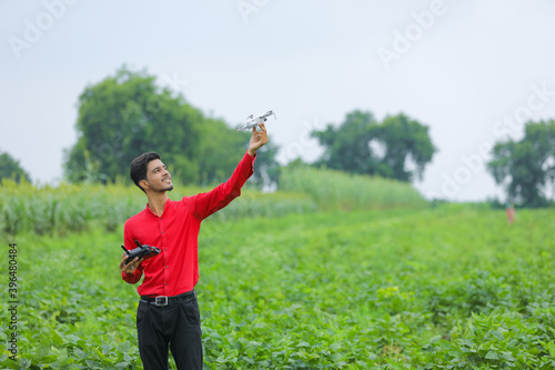Indian agronomist holding drone and remote in hand at agriculture field