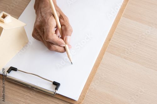 Close up senior asian old elderly man hand holding pencil for writing on paper to lecture or take note in wood carpenter concept