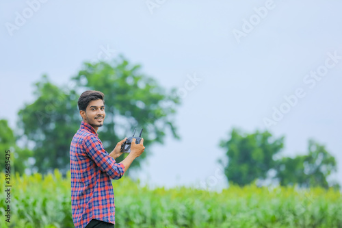 Young indian agronomist operate or control of flying drone at agriculture field
