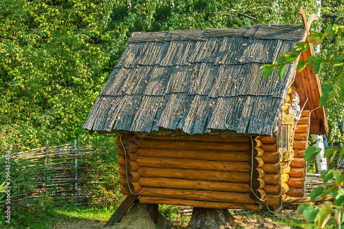 Decorative hut made of logs behind a wicker fence;
