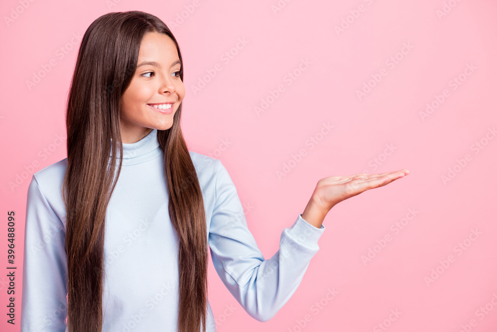 Photo of little school girl show arm palm looking empty space isolated on pastel pink color background Photo of little school girl show arm palm looking empty space isolated on pastel pink color background