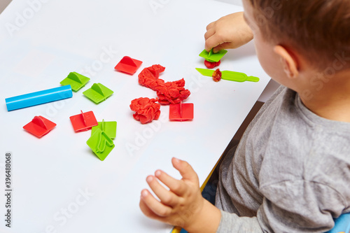 The boy is playing in his room. Young child playing with play doh or play dough. Educational toys for kid's. Games for Child Development.Child's hands kneading modelling clay. photo