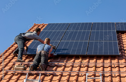 Workers installing solar electric panels on a house roof in  Ochojno. Poland photo
