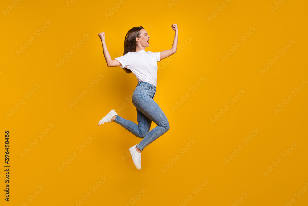 Full length body size photo of cheerful happy girl fan jumping high gesturing like winner shouting isolated bright yellow color background
