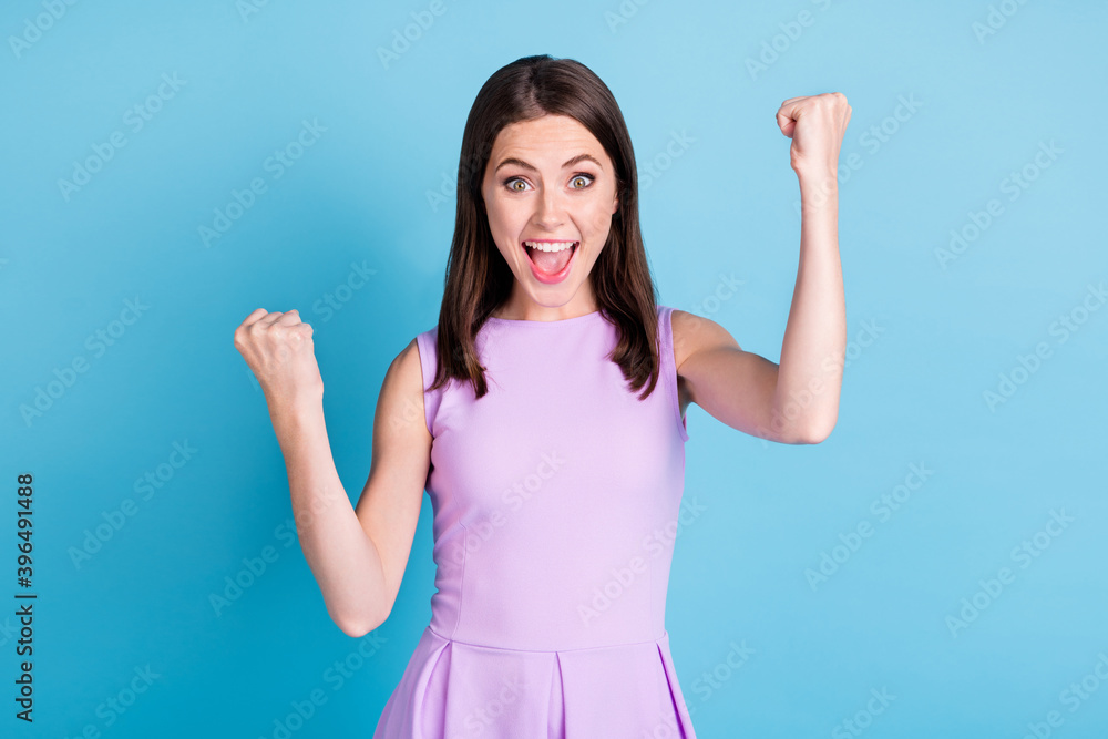 Photo of victorious positive young woman raise fists say yeah lucky win isolated on shine blue color background Photo of victorious positive young woman raise fists say yeah lucky win isolated on shine blue color background