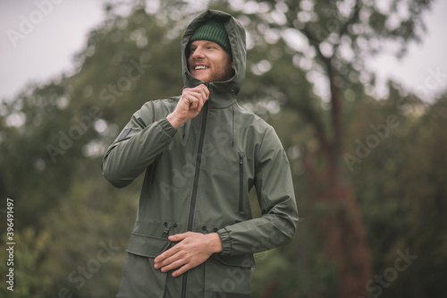Young man in a green coat standing in the rain photo