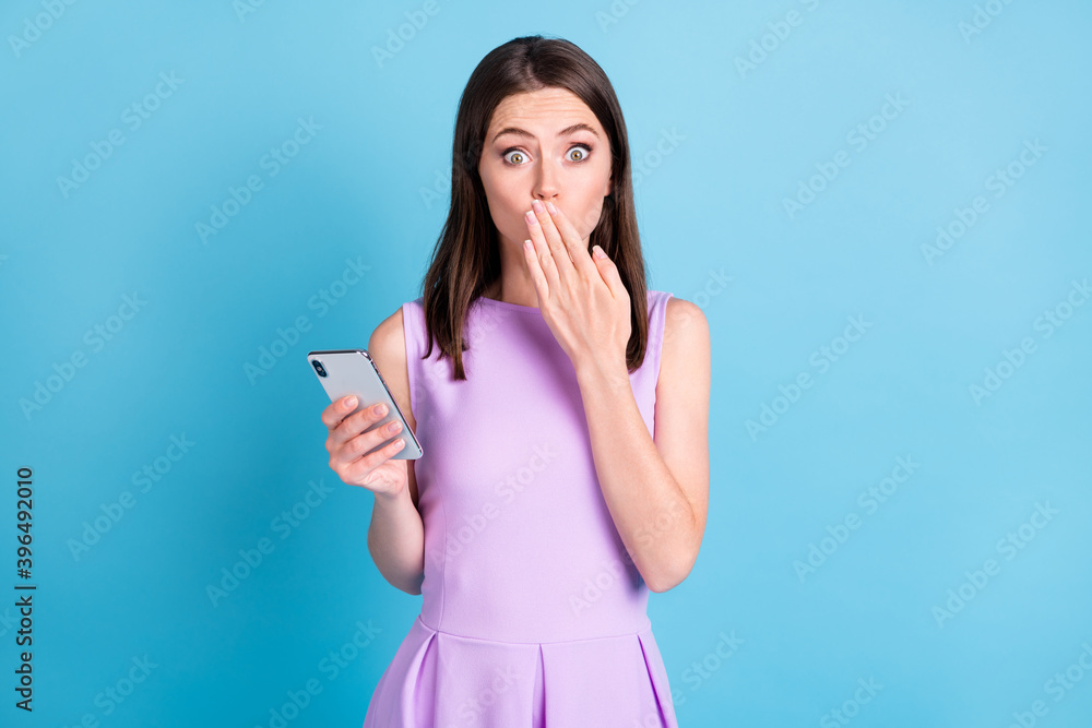 Photo of amazed guilty attractive young woman hold smartphone close hand mouth isolated on blue color background Photo of amazed guilty attractive young woman hold smartphone close hand mouth isolated on blue color background