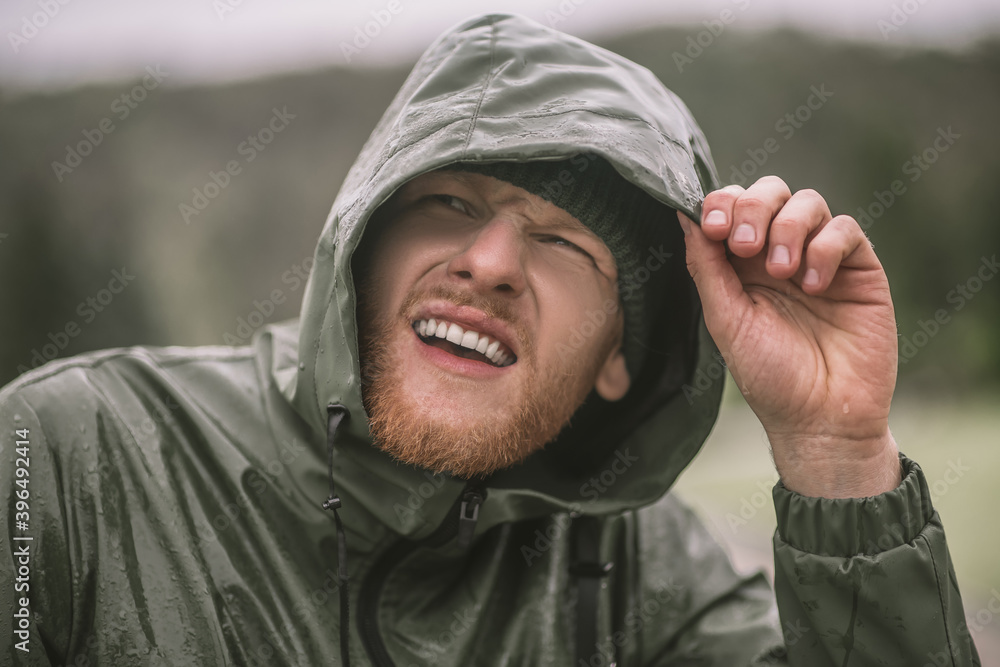 Young bearded man in a hood standing under the rain Young bearded man in a hood standing under the rain