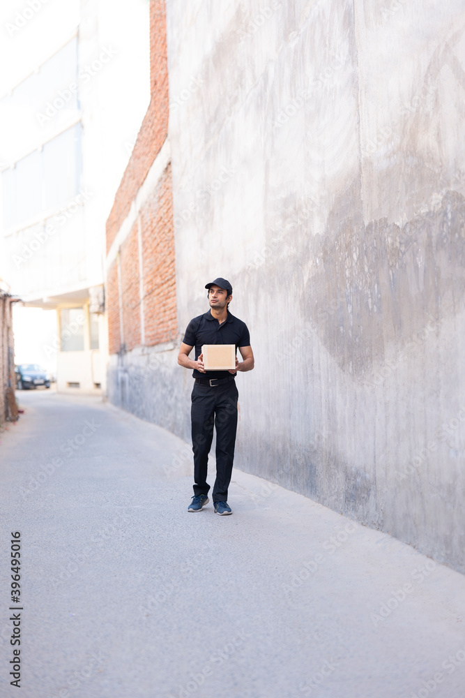 Delivery person standing on the road with a parcel in his hand Delivery person standing on the road with a parcel in his hand