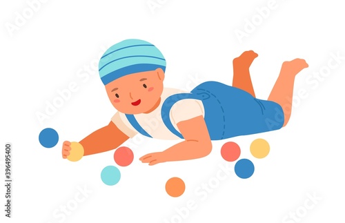Baby boy lying and playing with colorful bright balls. Cute toddler having fu...