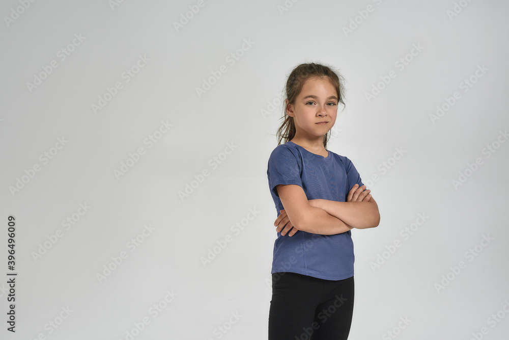 Little sportive girl child in sportswear looking at camera, while standing with arms crossed isolated over white background Little sportive girl child in sportswear looking at camera, while standing with arms crossed isolated over white background