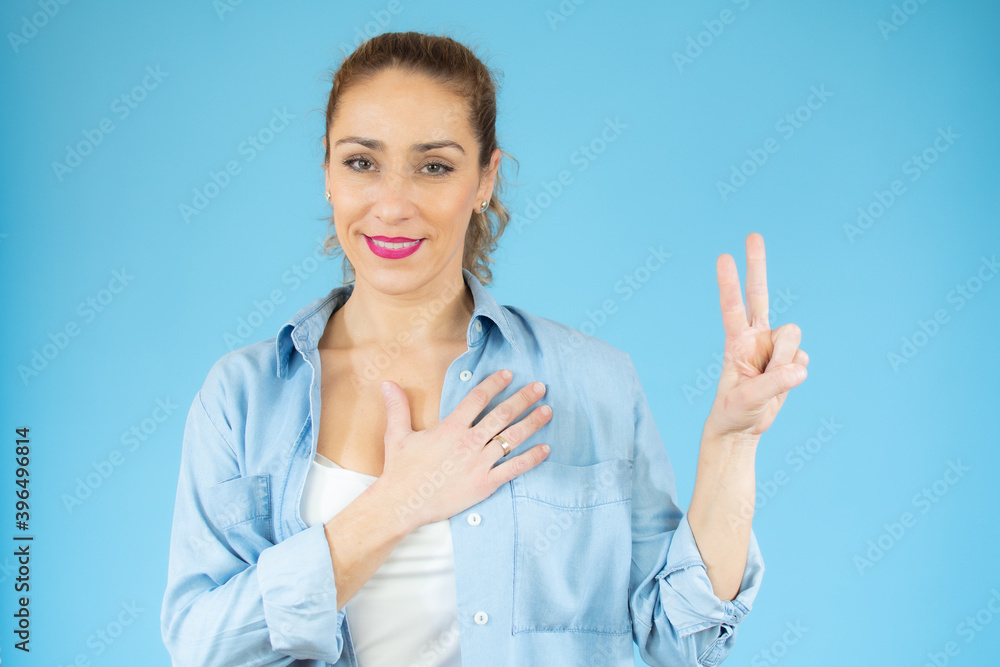 Young caucasian woman isolated showing victory sign and smiling over blue background. Young caucasian woman isolated showing victory sign and smiling over blue background.