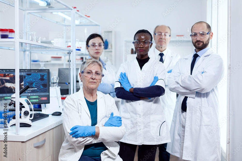 Portrait of head scientific project ar her research team holding arms crossed at workplace. African healthcare scientist in biochemistry laboratory wearing sterile equipment. Portrait of head scientific project ar her research team holding arms crossed at workplace. African healthcare scientist in biochemistry laboratory wearing sterile equipment.