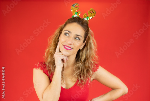 Beautiful woman wearing santa hat over isolated background confuse and wonder about question. Uncertain with doubt, thinking with hand on head. Pensive concept.