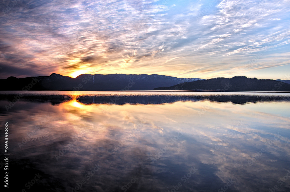 カルデラ湖の夕暮れ。外輪山の彼方に沈む夕陽の雄大な風景。