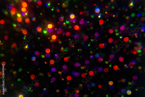 Christmas garland light. Colorful bokeh blurry decor on black background. Kaleidoscope ray. Holiday wallpaper night club party glowing. Dark overlay defocused holographic. Abstract blurred clipart
