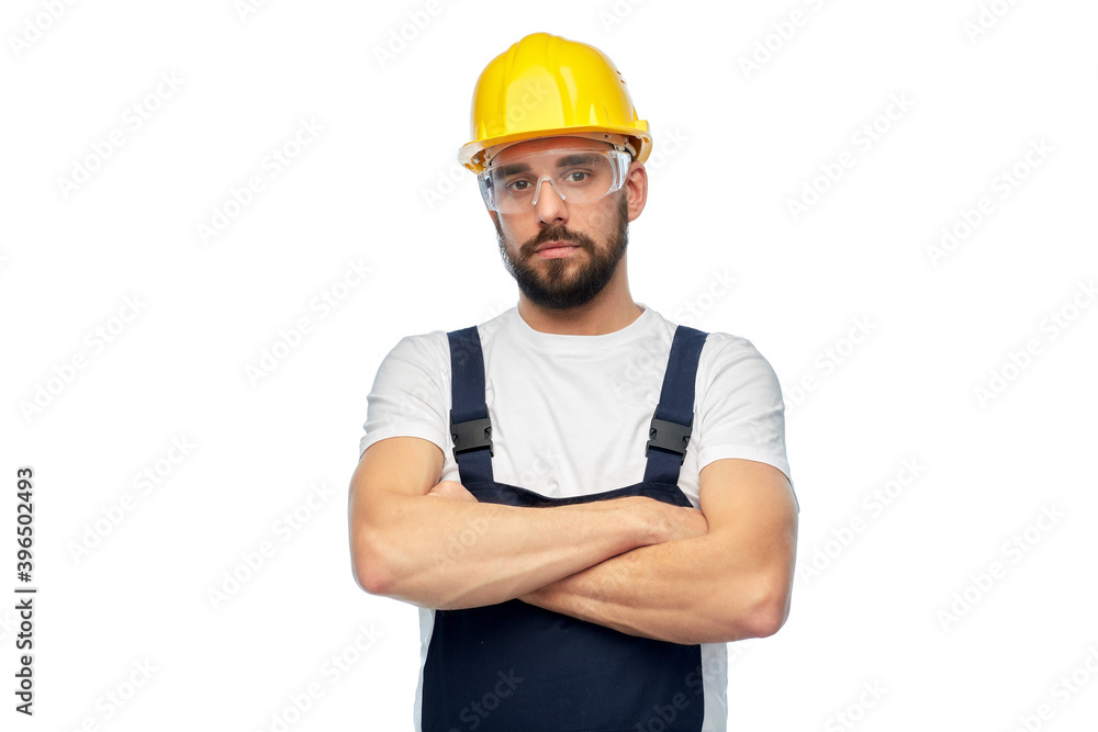 profession, construction and building - male worker or builder in yellow helmet and goggles with crossed arms over white background