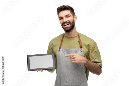 people, profession and job concept - happy smiling waiter or seller in apron showing tablet pc computer over white background photo