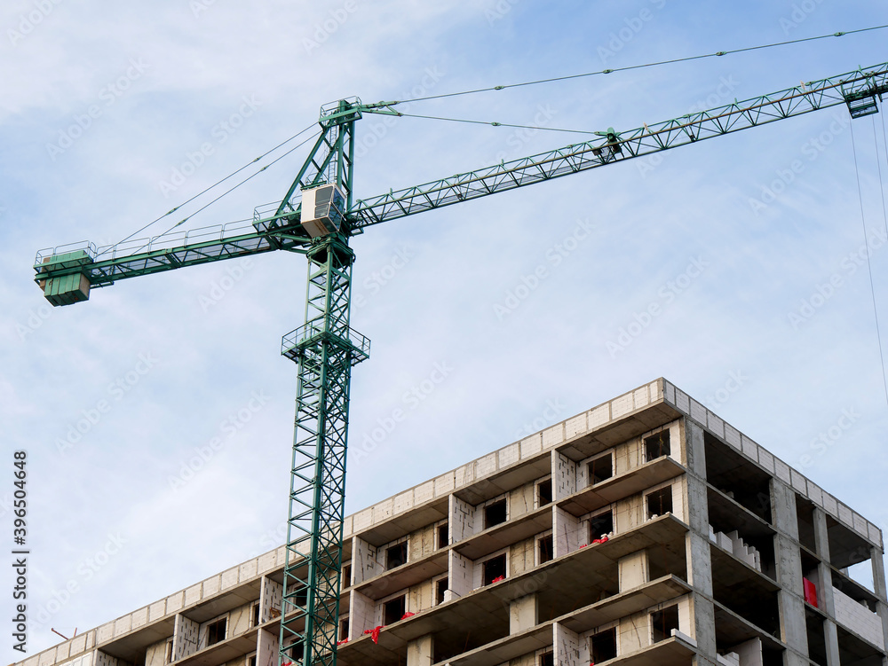 Construction site background. Hoisting crane and new multi-storey building. Industrial background.