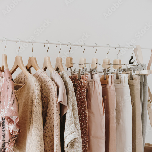 Minimal fashion clothes concept. Stylish female blouses, sweaters, pants, jeans and t-shirts on hanger on white background. Fashion blog, website, social media hero header.