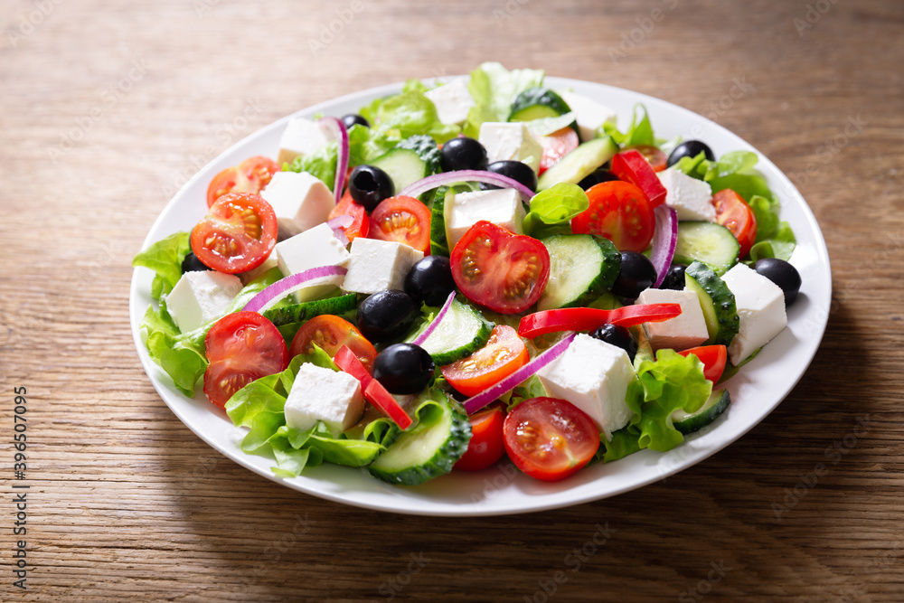 Plate of fresh salad with vegetables, feta cheese and olives. Greek salad.