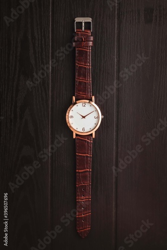 watch with brown leather strap on the wooden table