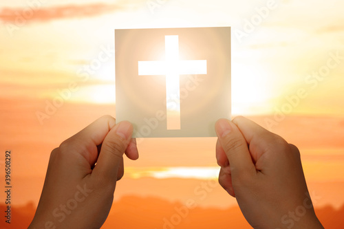 Human hand holding paper with a Christian cross